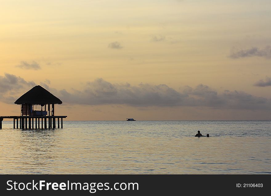 A hut on stilts at sunset in the Maldives