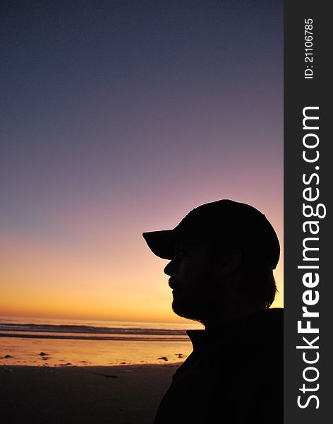 The sun sets during twilight at an Olympic Peninsula Beach, Washington, USA, and a man watches in silhouette. The sun sets during twilight at an Olympic Peninsula Beach, Washington, USA, and a man watches in silhouette.