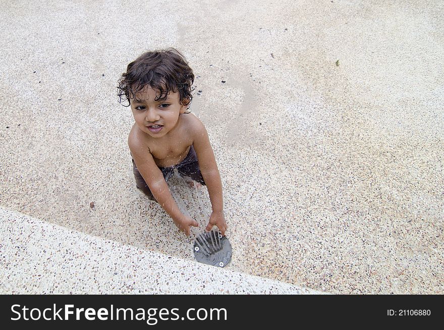 Photo of a smiling toddler playing with water fountain in a water park and enjoying summer. Photo of a smiling toddler playing with water fountain in a water park and enjoying summer