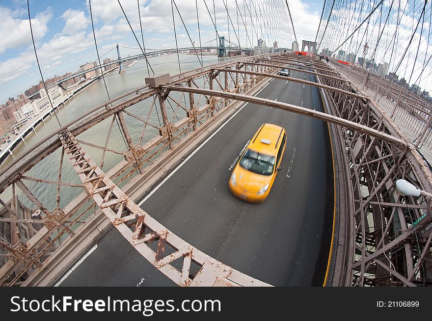 Wide angle photo of a yellow taxi on Brooklyn Bridge, New York