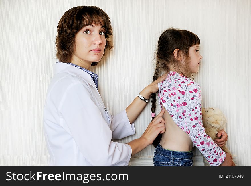 Young female doctor examines a little child girl on a white background. Young female doctor examines a little child girl on a white background