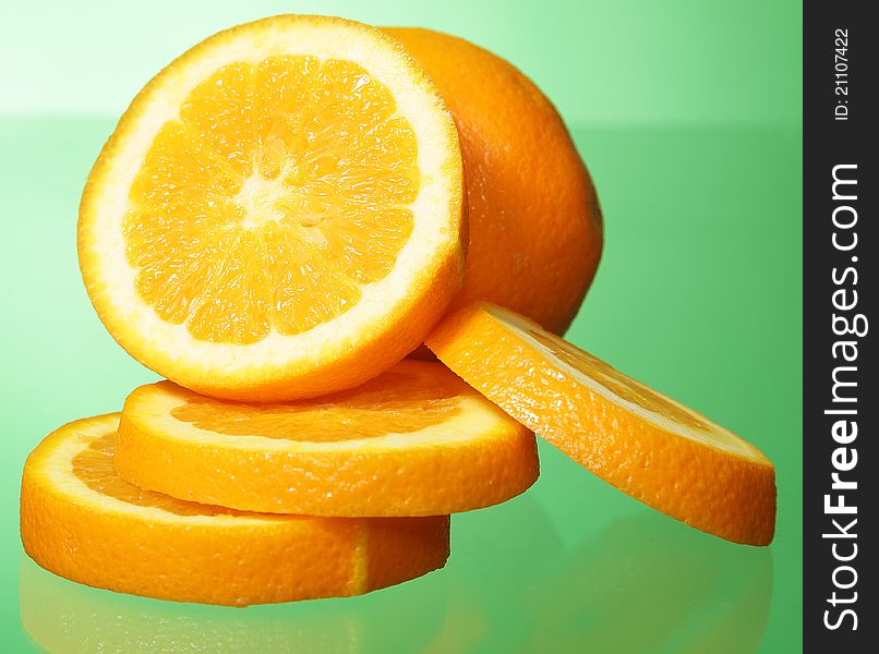 Orange and orange slices on green background.