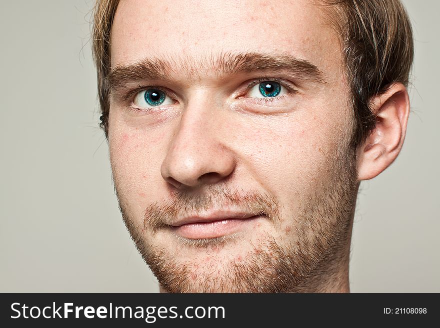 Young blond man with blue eyes on gray background looking confident. Young blond man with blue eyes on gray background looking confident