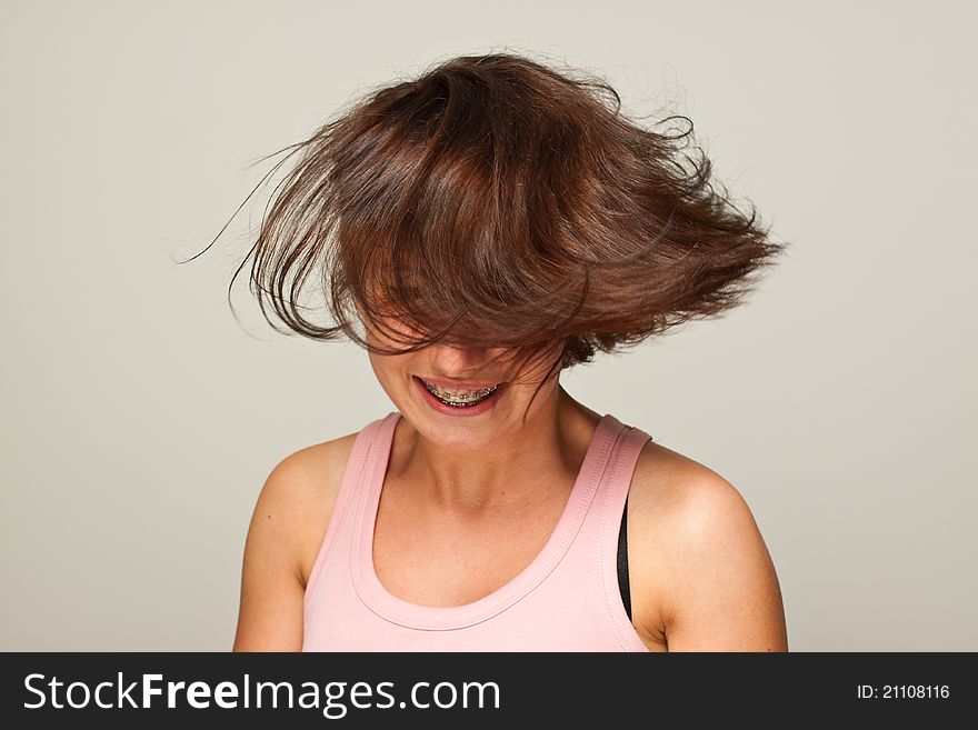 Woman waving her hair with retainer on gray background. Woman waving her hair with retainer on gray background