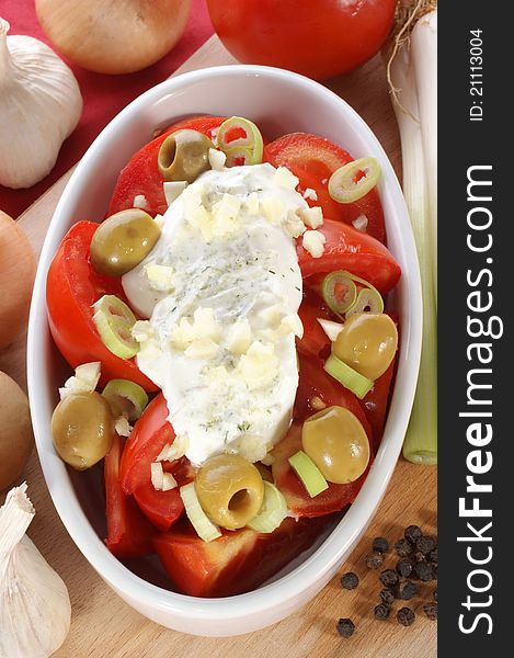 Tomato salad with herb yoghurt and olives in a bowl