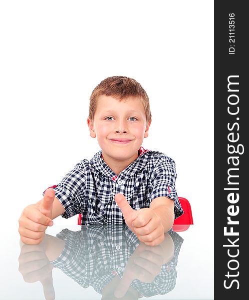 Young boy sitting near table and showing OK sign. Young boy sitting near table and showing OK sign