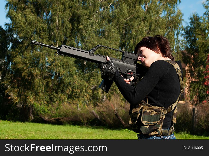 Beautiful girl with a gun to airsoft outdoors