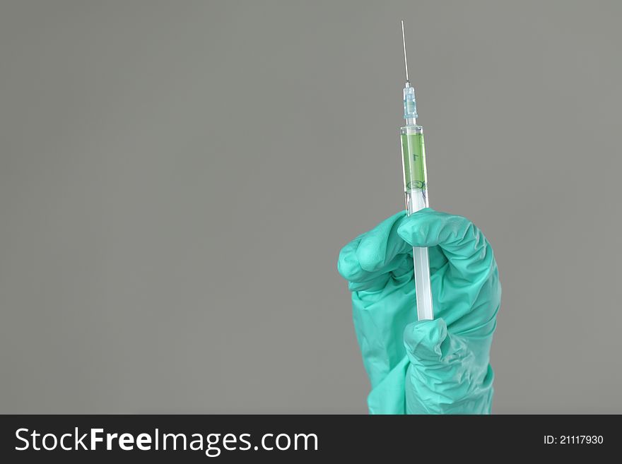 Syringe in hand on gray background