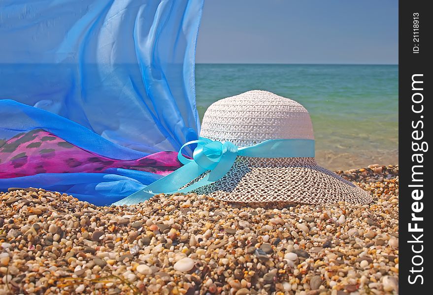 Straw woman hat and pareo on a beach with sea on background. Straw woman hat and pareo on a beach with sea on background