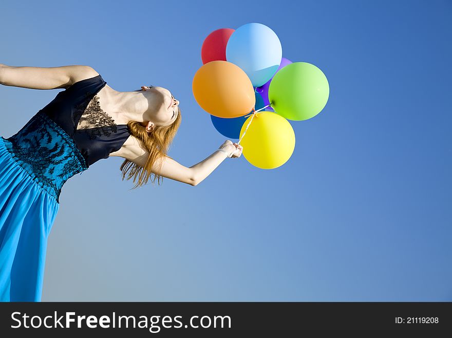 Redhead girl with colour balloons at blue sky background.