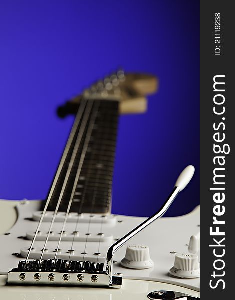 A white electric guitar isolated against a blue background with copy space. A white electric guitar isolated against a blue background with copy space