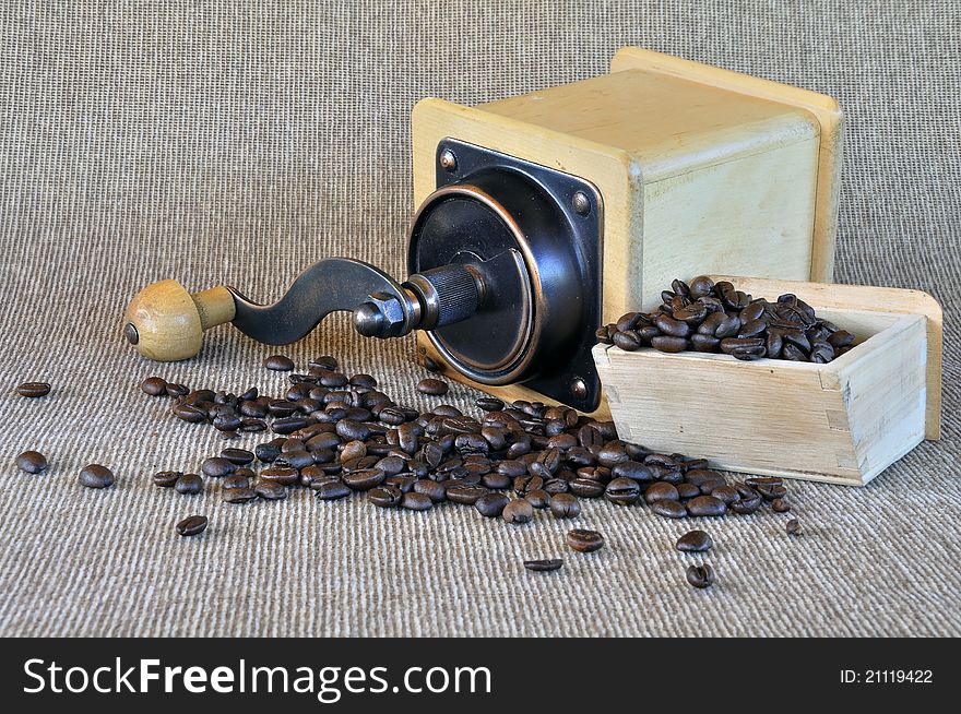 Coffee grinder and coffee beans on the light brown texture