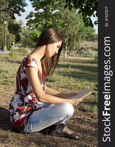Adult girl reading a book outdoors