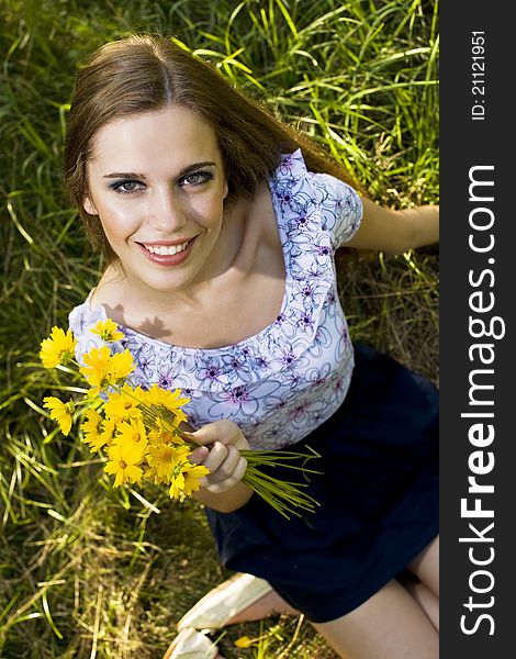 Portrait of a happy young girl smiling and holding orange flowers in her hands outdoor in summertime