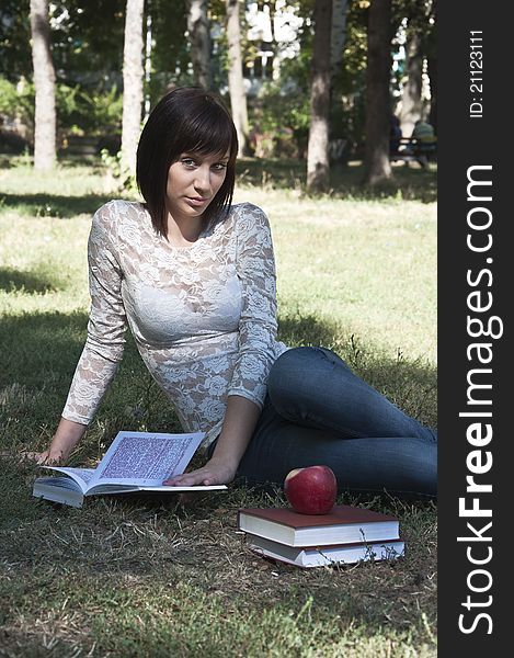 Young woman sitting on the grass and holding a book photographed in park. Young woman sitting on the grass and holding a book photographed in park