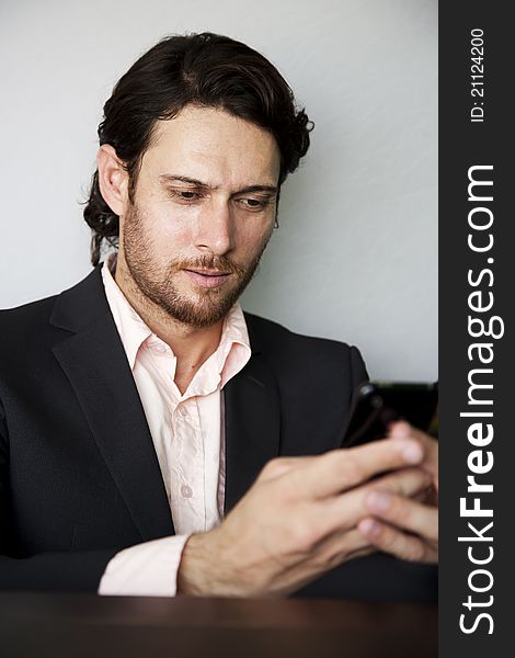 Young businessman sending an sms from his mobile phone. Young businessman sending an sms from his mobile phone