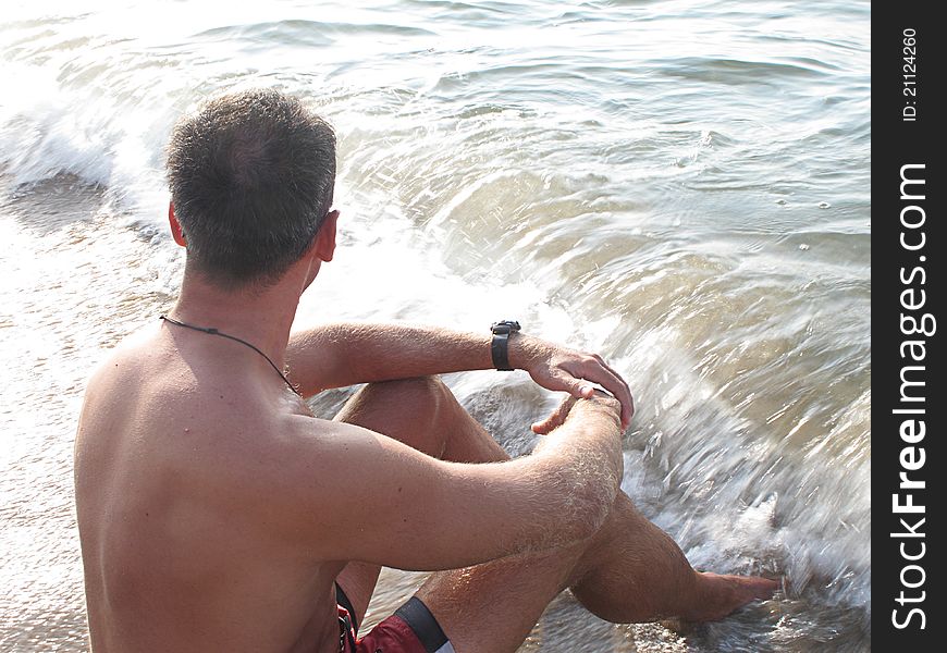 Boy sitting on the edge of the beach thinking