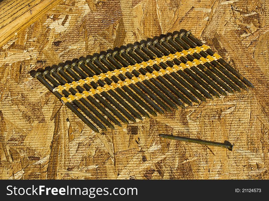 Row of gun nails on a plywood background.