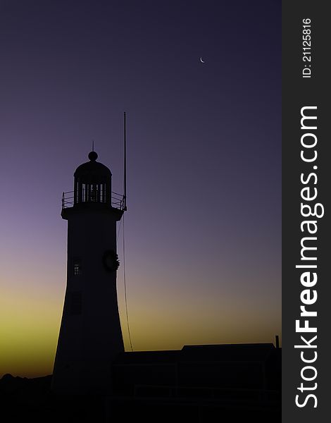 The Old Sictuate Lighthouse silhouette in Scituate, Massachusetts at dawn with the moon in the sky. The Old Sictuate Lighthouse silhouette in Scituate, Massachusetts at dawn with the moon in the sky.