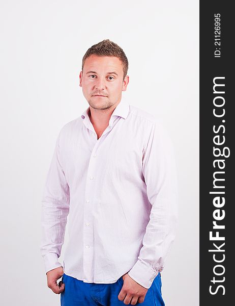 Portrait of casual young man, standing with hands in pocket, smiling. Isolated on white