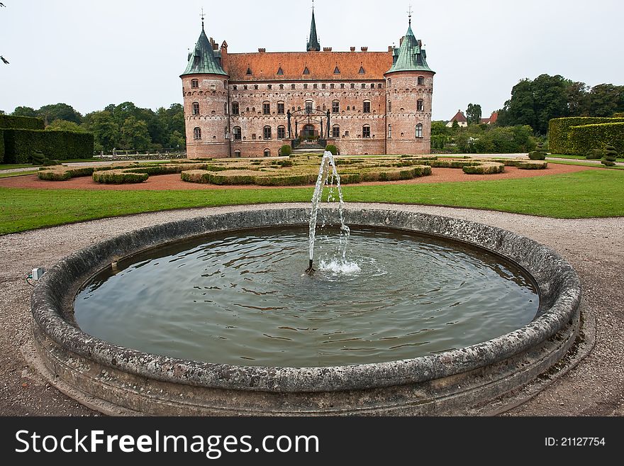 Egeskov castle slot landmark fairy tale castle in Funen Denmark view from the garden fountain. Egeskov castle slot landmark fairy tale castle in Funen Denmark view from the garden fountain