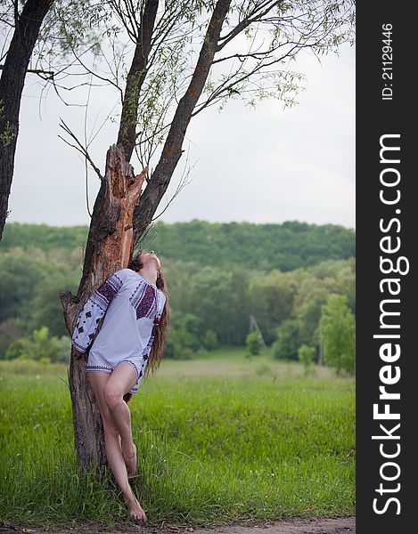 Portrait of sexy, lovely young girl in a beautiful national shirt standing next to a tree in an outdoor. Portrait of sexy, lovely young girl in a beautiful national shirt standing next to a tree in an outdoor