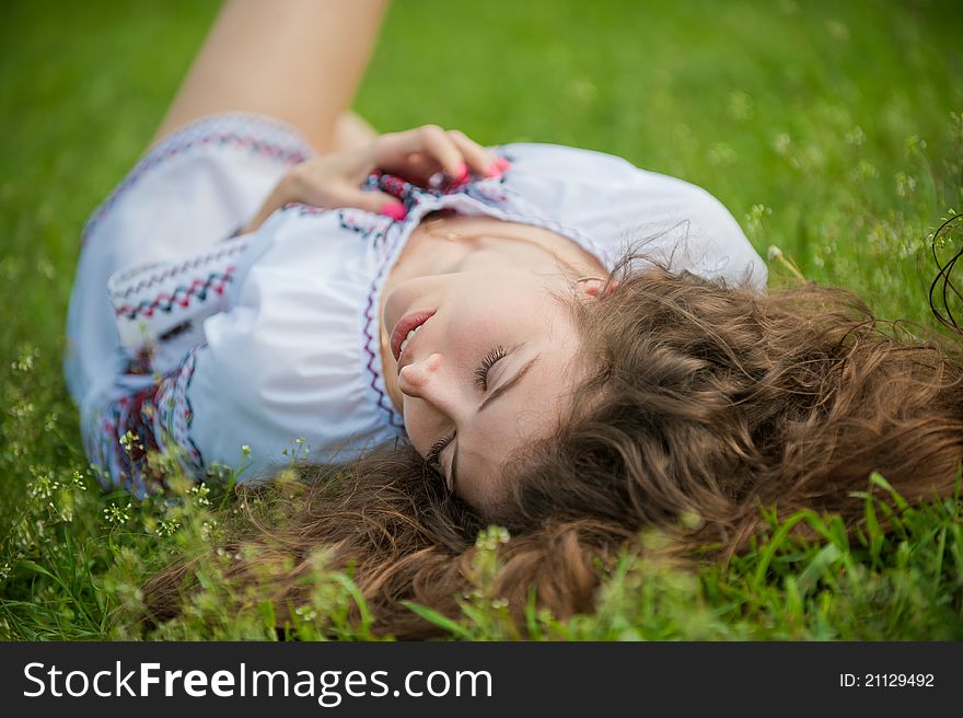 Portrait of a young sexually girl in the national shirt lying on the grass. Portrait of a young sexually girl in the national shirt lying on the grass