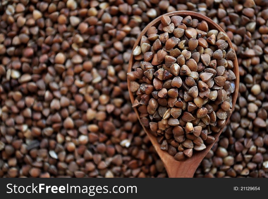 Buckwheat in a wooden spoon and forming a background.