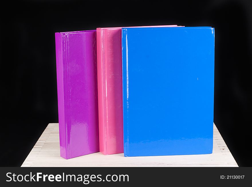 Three colorful books on a black background. Three colorful books on a black background
