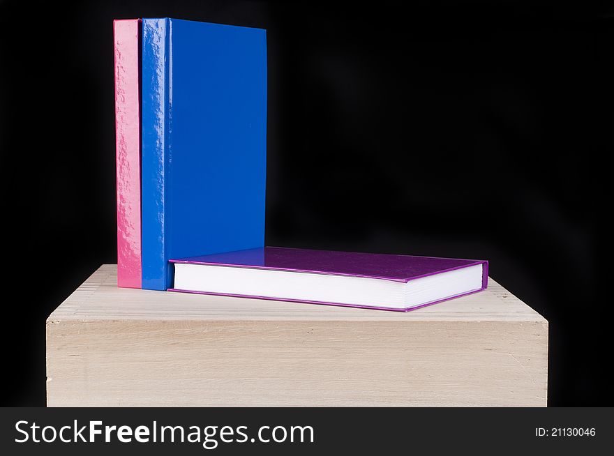 Three Colorful School Books On A Wooden Table