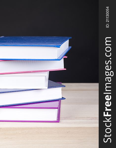 Pile of five colorful books on a wooden table