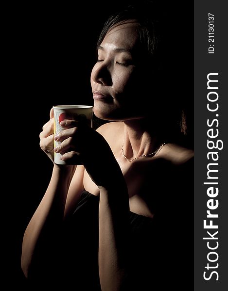 Attractive woman with an aromatic coffee in hands isolated on black background. Attractive woman with an aromatic coffee in hands isolated on black background