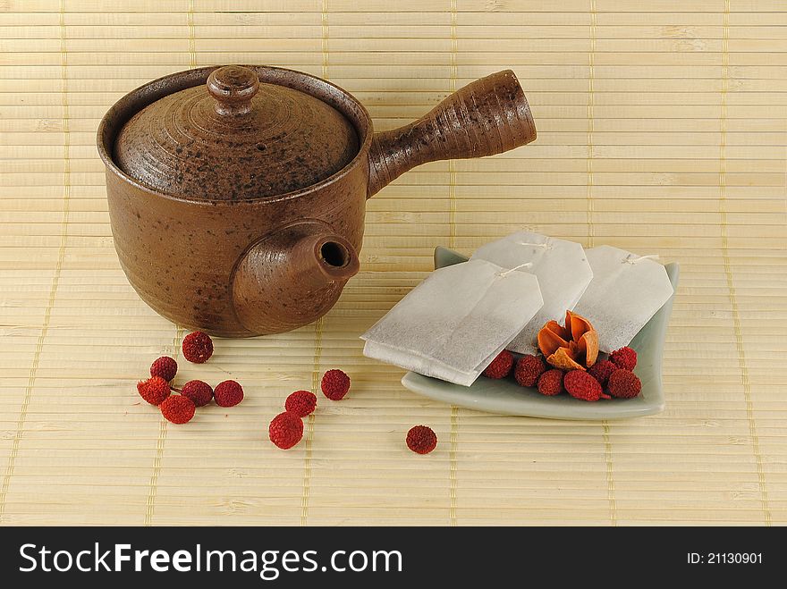 Teapot with tea bags on a little plate on bamboo background