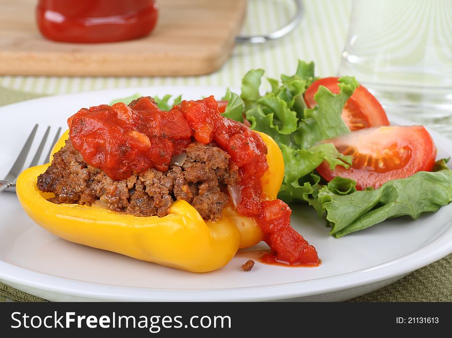 Baked stuffed yellow bell pepper with a salad on a plate. Baked stuffed yellow bell pepper with a salad on a plate