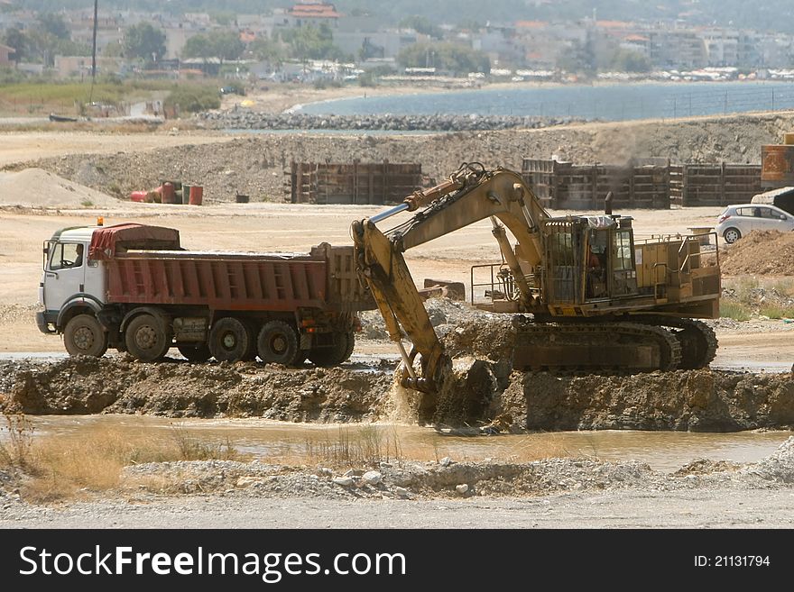 Bulldozer loading a truck on a construction yard