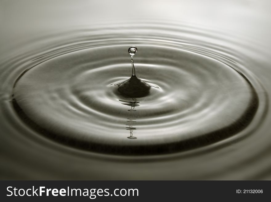 Water droplet and concentric ripples on a grey surface. Water droplet and concentric ripples on a grey surface.