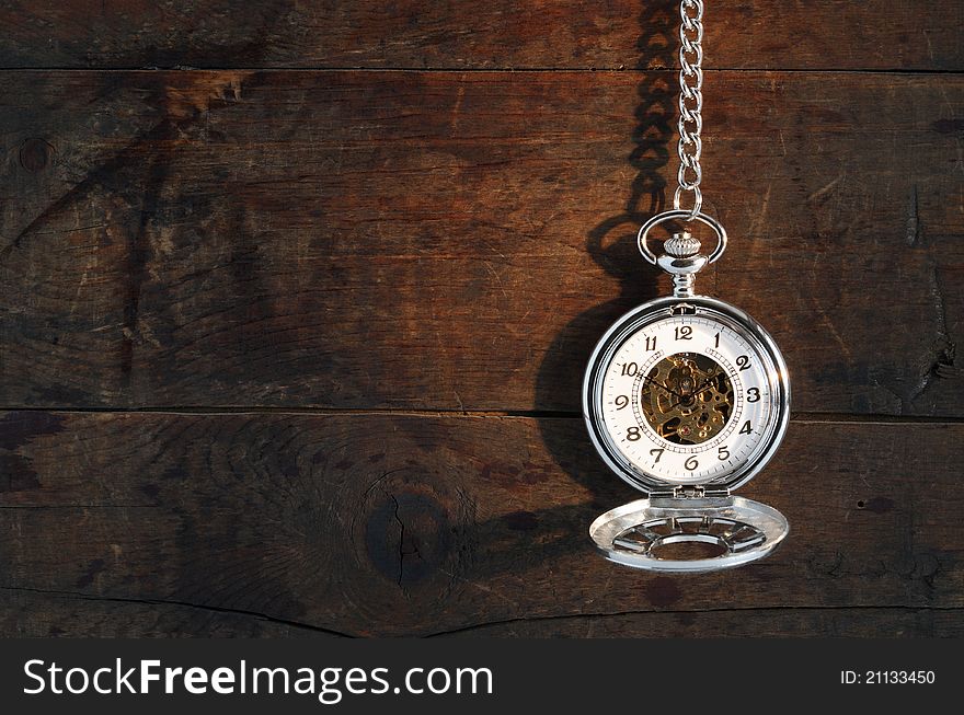Time concept. Stylish pocket watch hanging with chain against old wooden background. Time concept. Stylish pocket watch hanging with chain against old wooden background