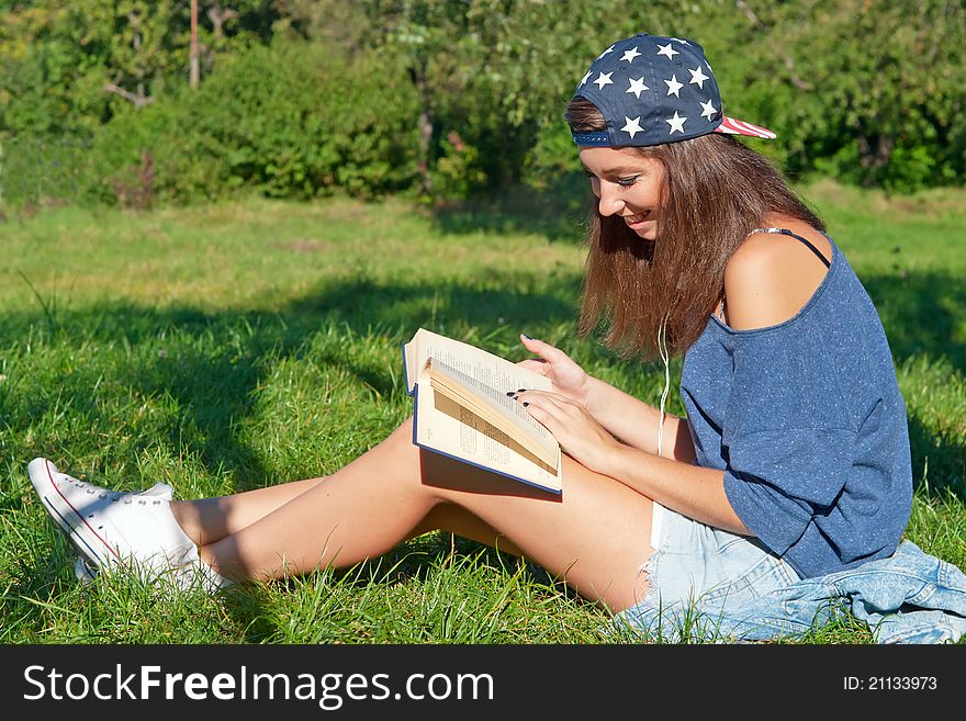 Girl with book sitting on a grass in the park. Girl with book sitting on a grass in the park