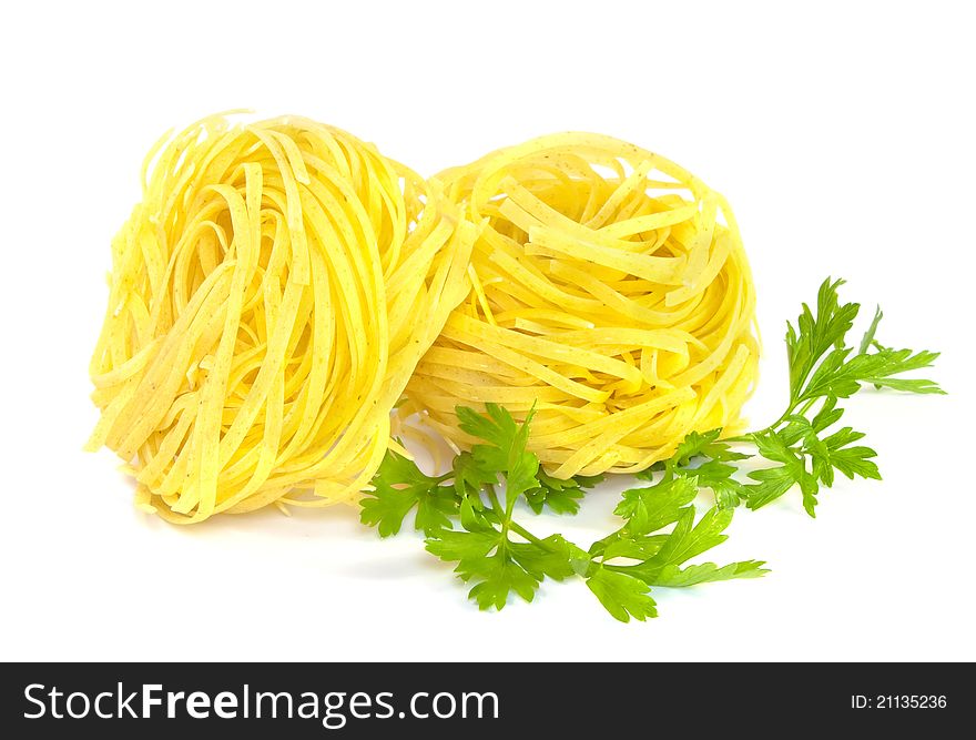 Two fettuccine pasta nests and green parsley on white background. Two fettuccine pasta nests and green parsley on white background