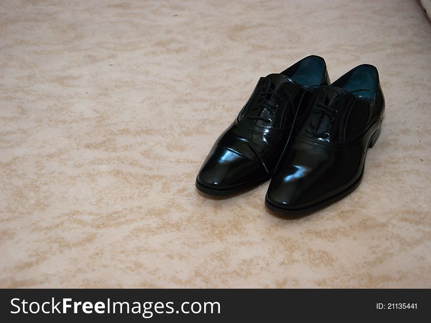 A groom's shoes on a floor. A groom's shoes on a floor