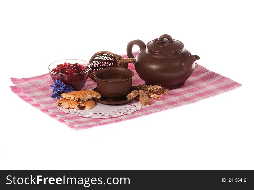 Teapot, cup of tea, biscuits and jam on red/pink checkered tablecloth isolated on white background. Teapot, cup of tea, biscuits and jam on red/pink checkered tablecloth isolated on white background