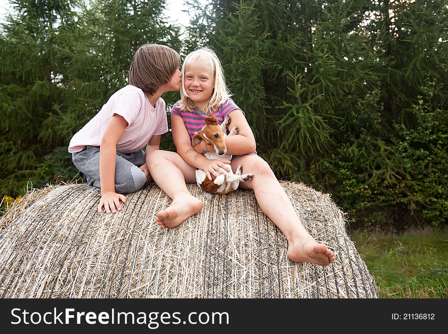 Two children and puppy, on huge bales of hay, and first kiss