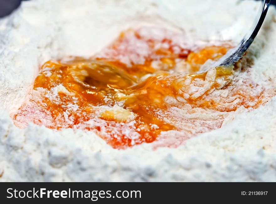A photo of en egg being stirred into flour. A photo of en egg being stirred into flour