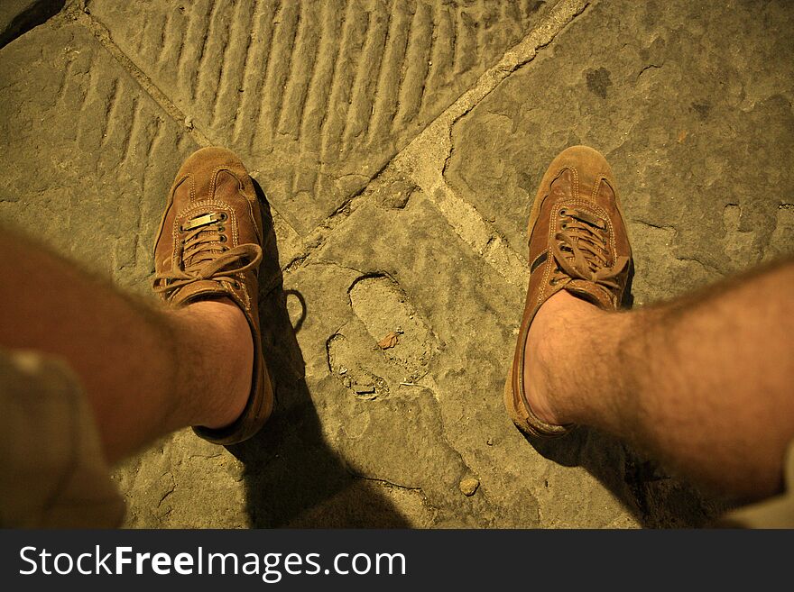Top view of feet in leisure shoes on pavement. Top view of feet in leisure shoes on pavement