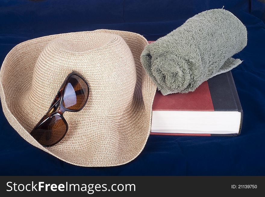 Everything you need for a day at the beach, straw hat,sun glasses,towel, and a book. Summer or Beach theme. Everything you need for a day at the beach, straw hat,sun glasses,towel, and a book. Summer or Beach theme