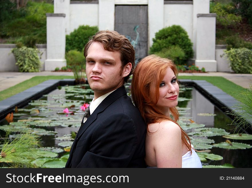 A bride and a groom sit by a lily pond. A bride and a groom sit by a lily pond