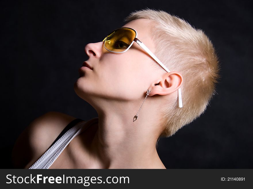 The young girl in yellow glasses on a black background