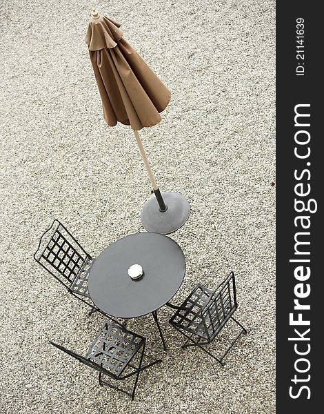 Iron outdoor table and chairs, with closed brown parasol. Iron outdoor table and chairs, with closed brown parasol