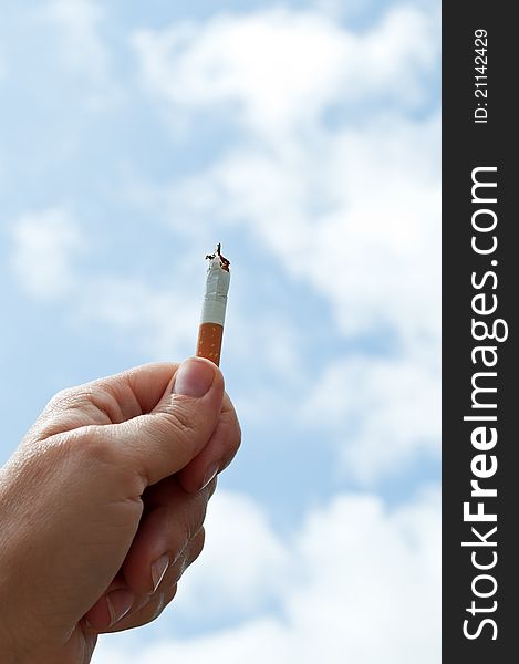 Holding a cigarette on the blue sky background