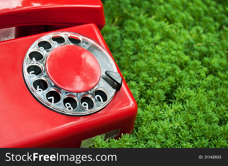 Red and old telephone on a green grass background. Red and old telephone on a green grass background